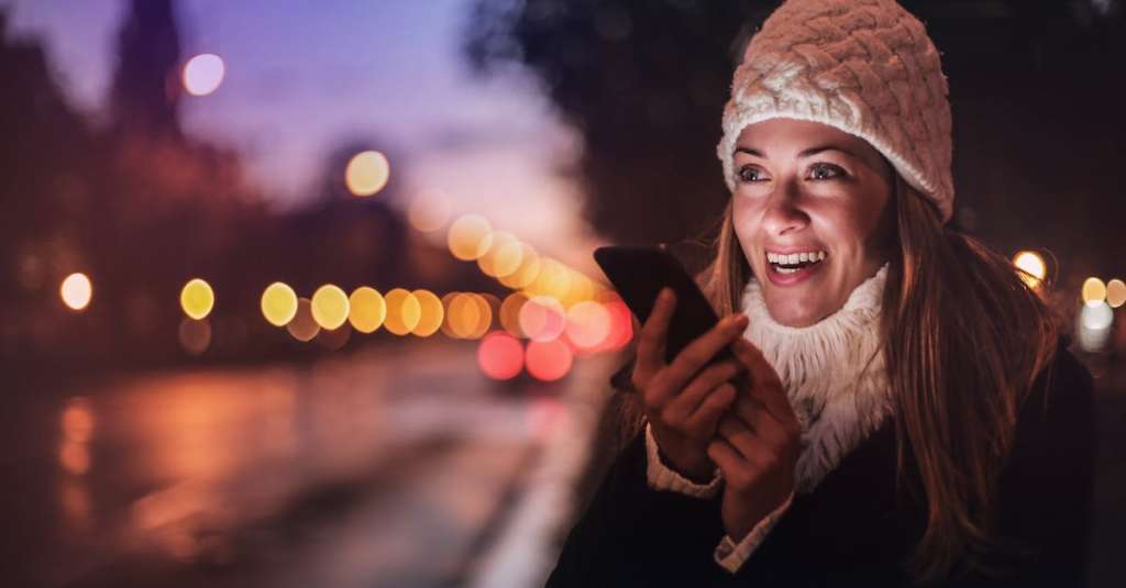 vrolijke-vrouw-spraakbericht-opnemen-op-smartphone-in-straat