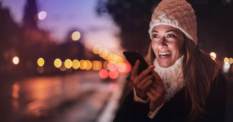 vrolijke-vrouw-spraakbericht-opnemen-op-smartphone-in-straat