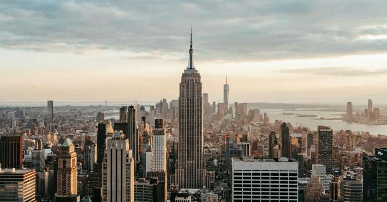 empire-state-building-in-de-buurt-van-wolkenkrabbers-onder-bewolkte-hemel