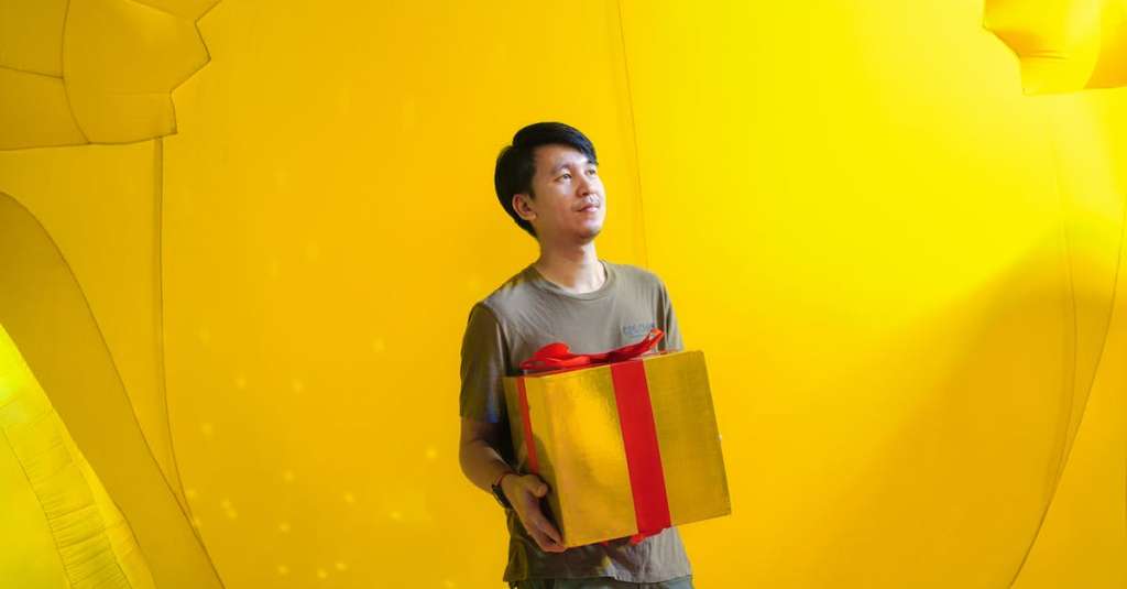 gratis-stockfoto-met-aziatische-kerel-cadeau-gele-achtergrond