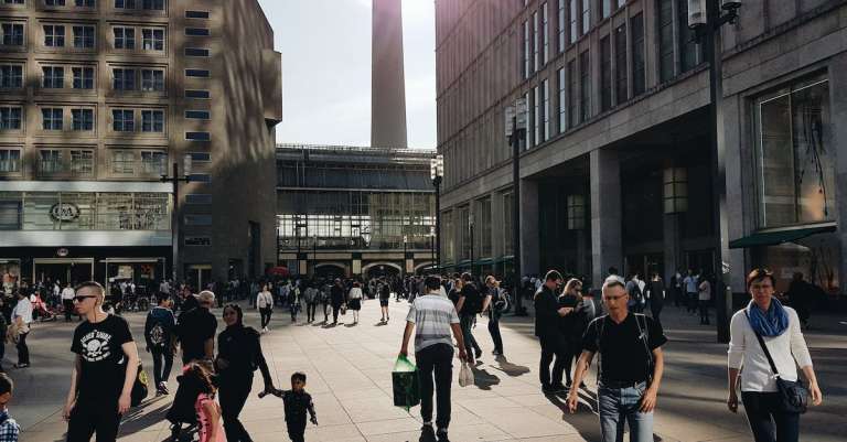 man-in-zwart-t-shirt-met-ronde-hals-die-dichtbij-gebouw-loopt