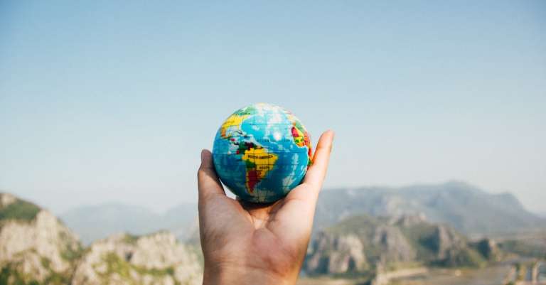 persoon-met-wereldbol-geconfronteerd-met-berg