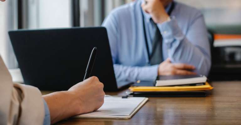 vrouw-sollicitatieformulier-in-kantoor-met-baas-invullen