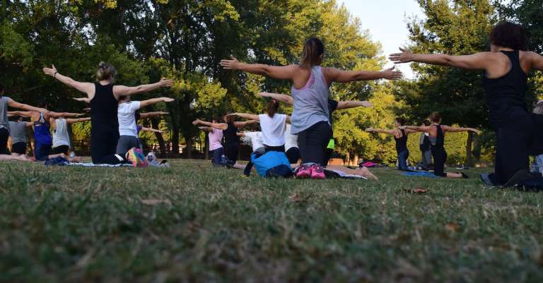 vrouwen-uitvoeren-van-yoga-op-groen-gras-in-de-buurt-van-bomen