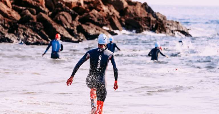 onherkenbare-sporters-in-natte-pakken-zwemmen-in-schuimende-oceaan